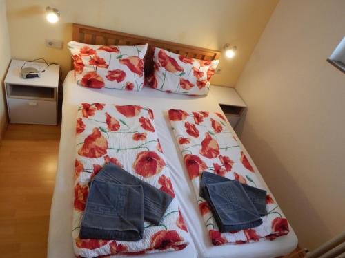 um quarto com duas camas com flores vermelhas em Appartement zur Bergoase mi Schwimmbad em Hohegeiß