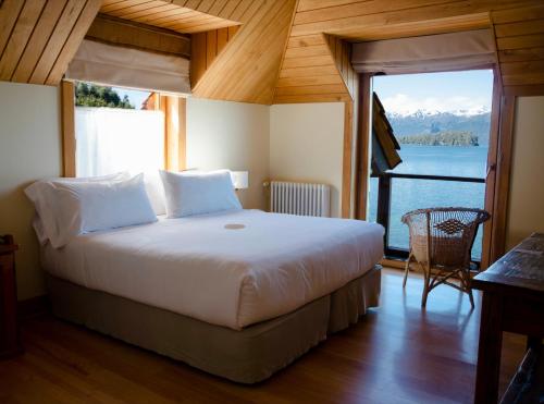 Dormitorio con cama y vistas al agua en Correntoso Lake & River Hotel en Villa La Angostura