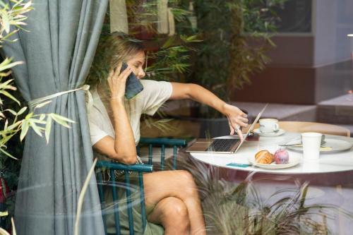 Eine Frau, die am Tisch sitzt und auf einem Handy redet. in der Unterkunft 21 House of Stories Città Studi in Mailand