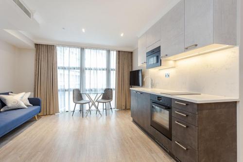 a kitchen with a blue couch and a table with chairs at Cleveland Residences Farringdon in London