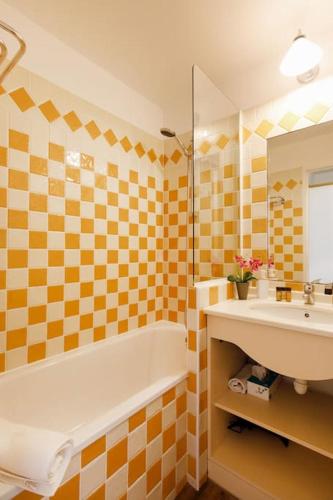 une salle de bain avec une baignoire, un lavabo et un miroir dans l'établissement Chagall 3 étoiles YourHostHelper, à Cannes