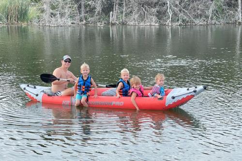 a man and four children sitting in a raft on a river at Reflection Cabin on Lake Godstone in Jacksboro