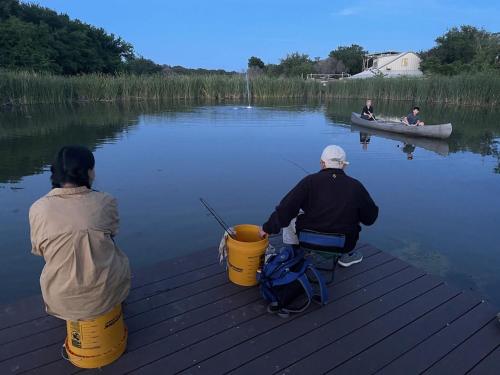 two people sitting on a dock with a boat in the water at Reflection Cabin on Lake Godstone in Jacksboro