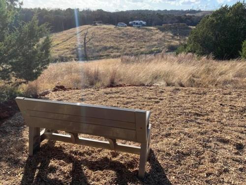 a wooden bench sitting in a field with a hill at Reflection Cabin on Lake Godstone in Jacksboro