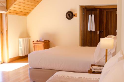 a bedroom with two beds and a lamp and a door at Correntoso Lake & River Hotel in Villa La Angostura