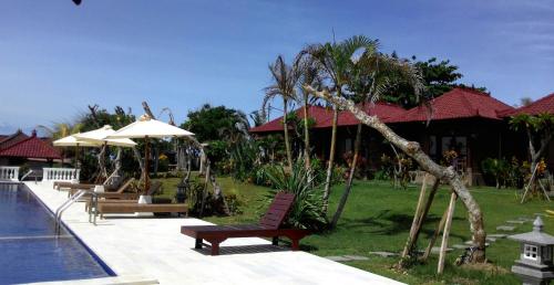 a resort with a pool and benches next to a house at Gubug Balian Beach Bungalow in Selemadeg