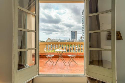 ein offenes Fenster mit einem Tisch und Stühlen auf dem Balkon in der Unterkunft Casa Gracia Apartments in Barcelona