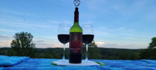 a bottle of wine and two glasses on a table at Tentrr Signature Site - Little Creek Ranch in Waynesboro