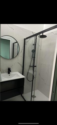 une salle de bain avec un lavabo et une douche avec un miroir dans l'établissement La marine 2, à Deauville