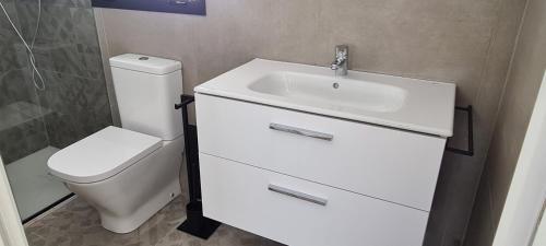 uma casa de banho com um lavatório branco e um WC. em Ático Corazones em Granada