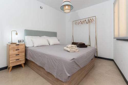 a bedroom with a bed and a wooden dresser and a lamp at Appartamento SOL Y PLAYA a El Cotillo. in Cotillo