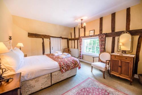 1 dormitorio con cama, escritorio y espejo en Bridge House in Kersey, en Ipswich