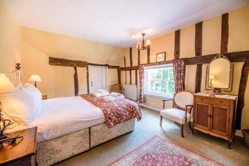 a bedroom with a bed and a desk and a mirror at Bridge House in Kersey in Ipswich