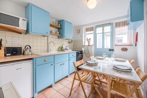a kitchen with blue cabinets and a table with chairs at The Bolt Hole in Southwold in Southwold