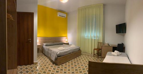 - une chambre avec un lit et un mur jaune dans l'établissement Erythrà Bed and Breakfast, à Reggio de Calabre