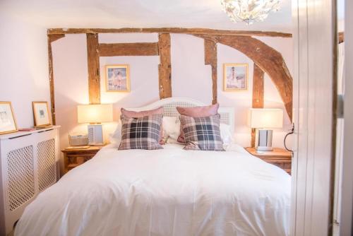 a bedroom with a white bed with pillows and two lamps at Rose Cottage in Lavenham in Lavenham