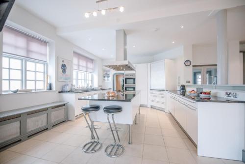 a large kitchen with white cabinets and stools in it at The Links in Southwold in Southwold