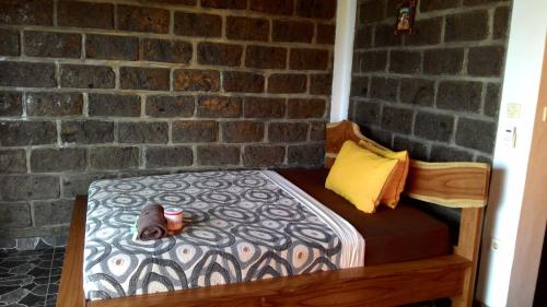 a bedroom with a bed with a brick wall at Gubug Balian Beach Bungalow in Selemadeg