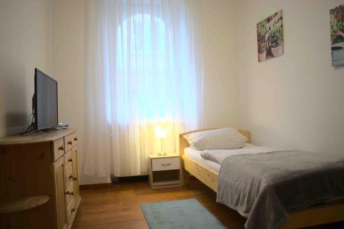 a bedroom with a bed and a television and a window at Goldstadt Ferienwohnung in Pforzheim