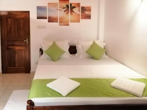 a bedroom with a bed with green and white pillows at Villa One64 Beach Front - Apartments in Hikkaduwa