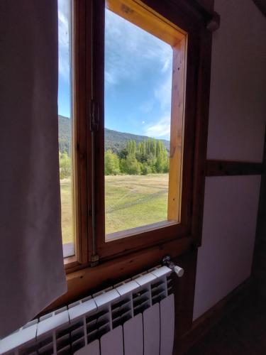 a window in a room with a view of a field at Origenes Ecolodge de Montaña in El Bolsón