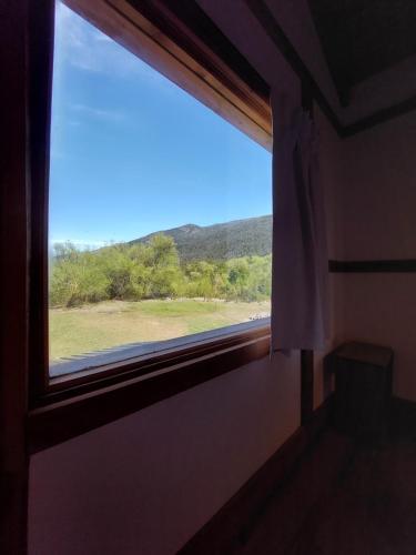 a window in a room with a view of a field at Origenes Ecolodge de Montaña in El Bolsón