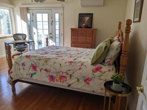 a bedroom with a bed with a floral bedspread at A lake, a mountain and the house with the red door in Clearlake