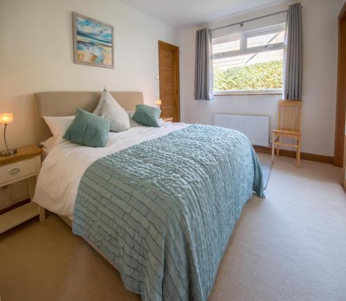 a bedroom with a bed with a blue blanket and a window at White Sands in Swanage