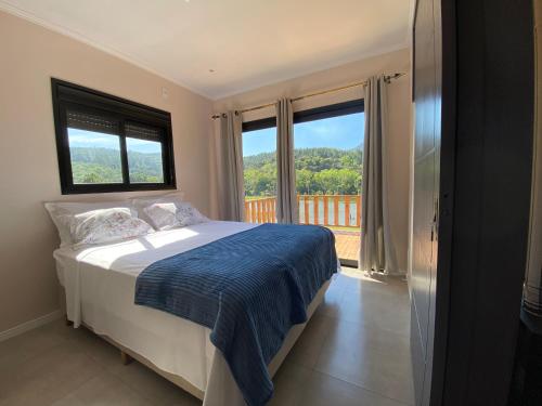 a bedroom with a bed with a view of a balcony at Casa na Serra Gaúcha in Igrejinha