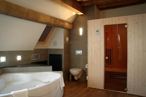 a large bathroom with a tub and a toilet at Hotel Van Eyck in Maaseik