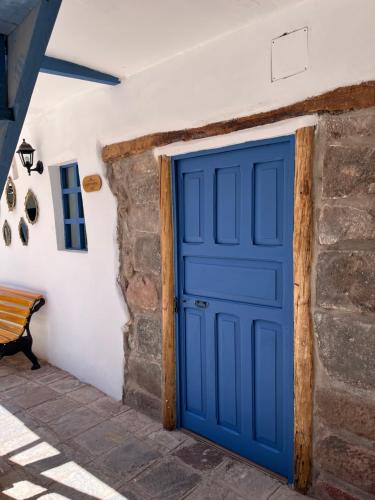a blue door in a white wall with a bench at CASA CRISTOBAL Siete Cuartones in Cusco