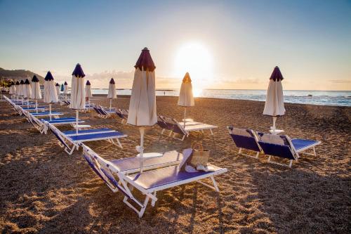 a row of chairs and umbrellas on a beach at Grand Hotel Diana Majestic in Diano Marina