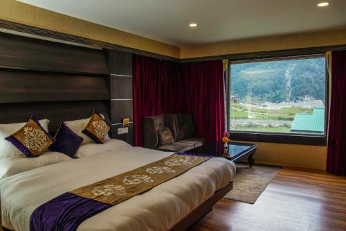 um quarto de hotel com uma cama e uma grande janela em Arco Hotels & Resorts sonamarg em Sonamarg