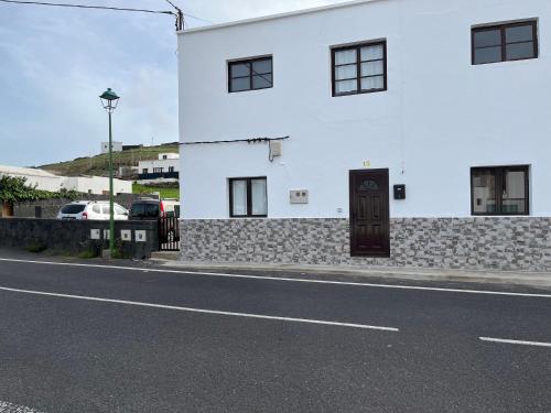 a white building with a door on the side of a street at Casa de campo Yuco in Tinajo