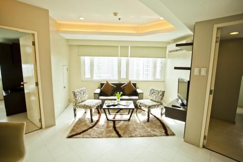 a living room with a couch and a table and chairs at The Exchange Regency Residence Hotel Managed by HII in Manila