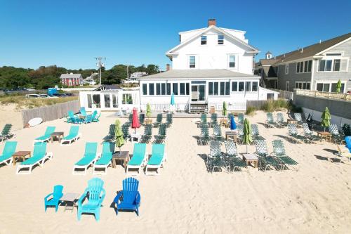 un montón de sillas y sillas en la playa en By The Sea Guests Bed & Breakfast and Suites en Dennis Port