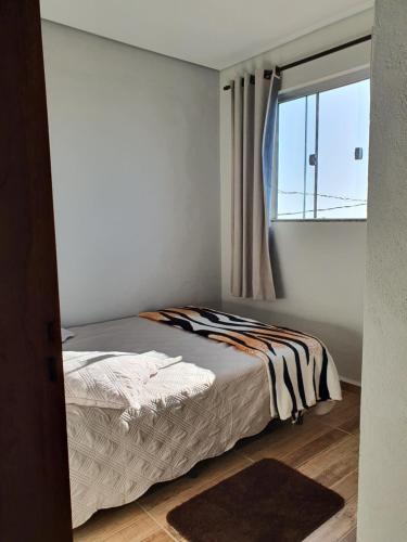 a bedroom with a bed and a window at Suítes Nativa STL in São Thomé das Letras