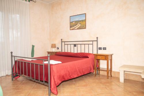 um quarto com uma cama com um cobertor vermelho e uma mesa em Agriturismo l'Ovile em San Michele