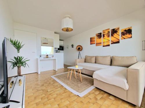 a living room with a couch and a table at Appartement 1ere ligne piscine terrasse au bord de la plage front de mer avec 6 vélos in Palavas-les-Flots
