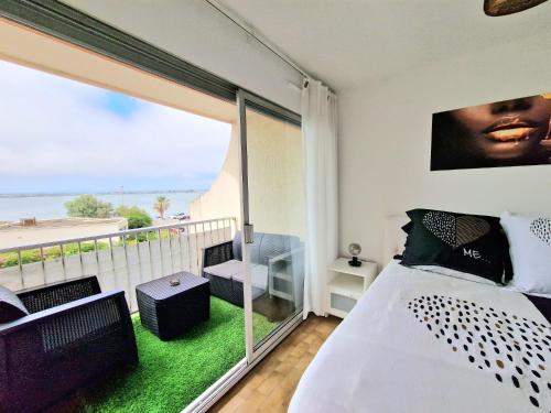 1 dormitorio con 1 cama y balcón con vistas. en Appartement 1ere ligne piscine terrasse au bord de la plage front de mer avec 6 vélos en Palavas-les-Flots
