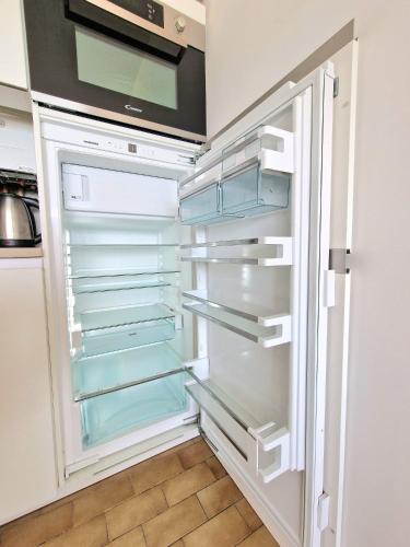 an empty refrigerator with its door open in a kitchen at Appartement 1ere ligne piscine terrasse au bord de la plage front de mer avec 6 vélos in Palavas-les-Flots