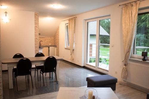 Una sala de estar con mesa y sillas y ventanas. en Apartamenty Panorama, en Rychwałd