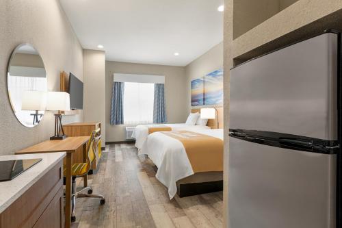 a hotel room with two beds and a refrigerator at Days Inn & Suites by Wyndham Greater Tomball in Tomball