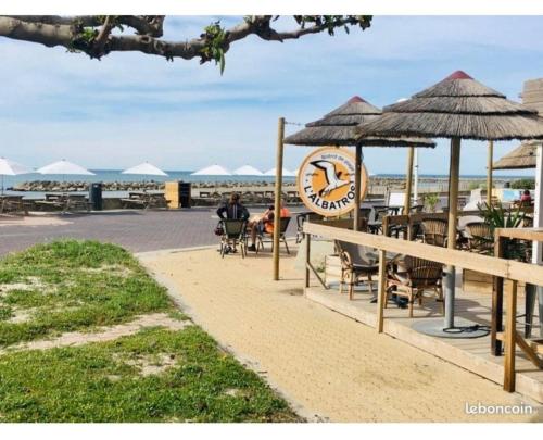a clock on the side of a beach with tables and chairs at Appartement 1ere ligne piscine terrasse au bord de la plage front de mer avec 6 vélos in Palavas-les-Flots