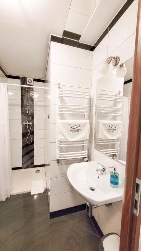 a white bathroom with a shower and a sink at Apartamenty Panorama in Rychwałd