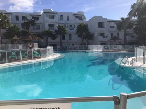 una gran piscina de agua azul frente a un edificio en casa de los amigos en Tías