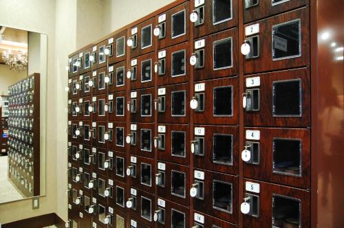 a wall filled with lots of cell phones at Anshin Oyado Ginza Shimbashi Station - For Men in Tokyo