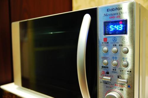 a microwave oven with a clock on top of it at Anshin Oyado Ginza Shimbashi Station - For Men in Tokyo