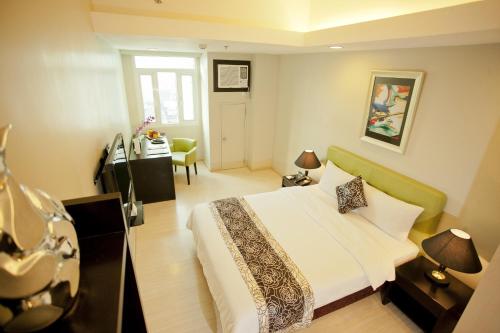 a hotel room with a bed and a desk at The Exchange Regency Residence Hotel Managed by HII in Manila