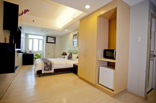 a hotel room with a bed and a tv at The Exchange Regency Residence Hotel Managed by HII in Manila